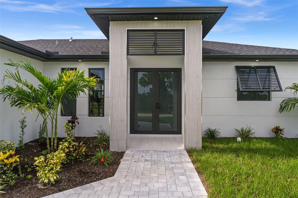The exterior of a modern home features a double front door under a tiled entryway — 1609 NW 16TH TERRACE, CAPE CORAL, FL