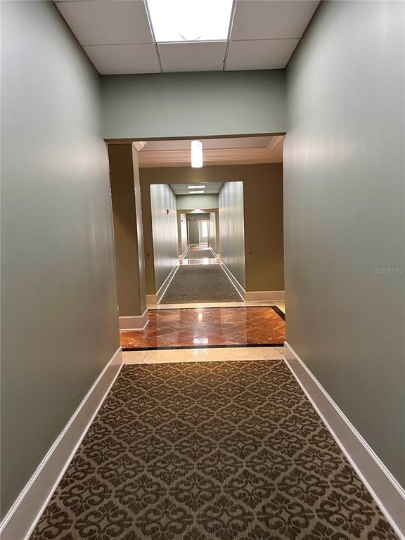 A long hallway features patterned carpet, light green walls, and a transition to marble flooring — 7065 WESTPOINTE BOULEVARD UNIT 303 & 304, ORLANDO, FL