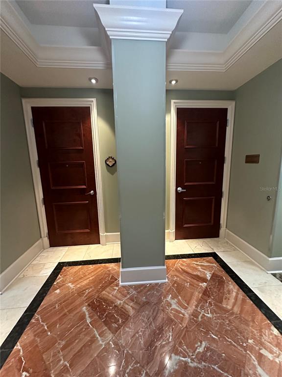 A hallway features two dark wood doors separated by a central pillar on marble flooring — 7065 WESTPOINTE BOULEVARD UNIT 303 & 304, ORLANDO, FL