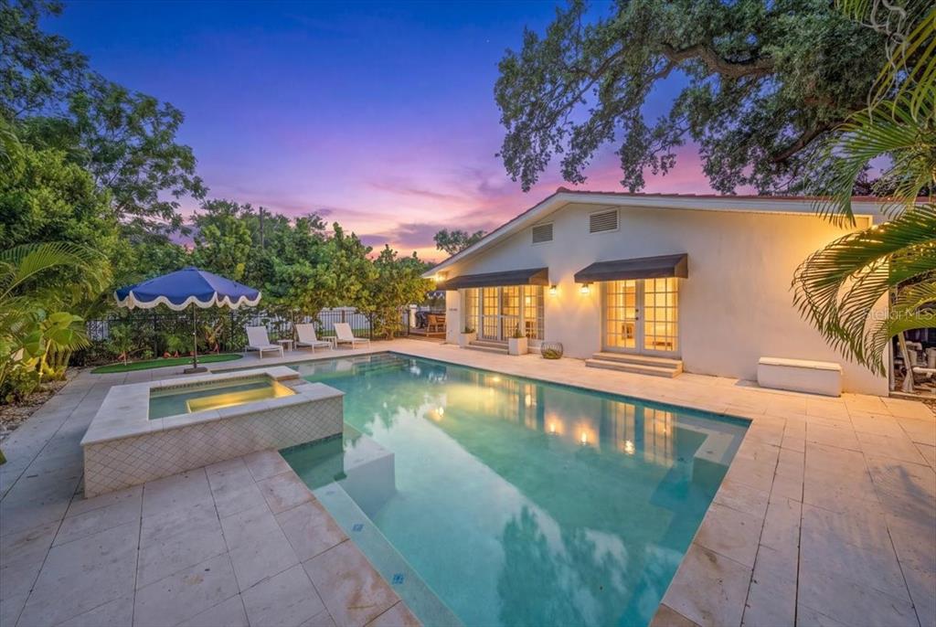 A backyard features a swimming pool with an attached spa and a white house exterior — 222 26TH AVENUE S, ST PETERSBURG, FL