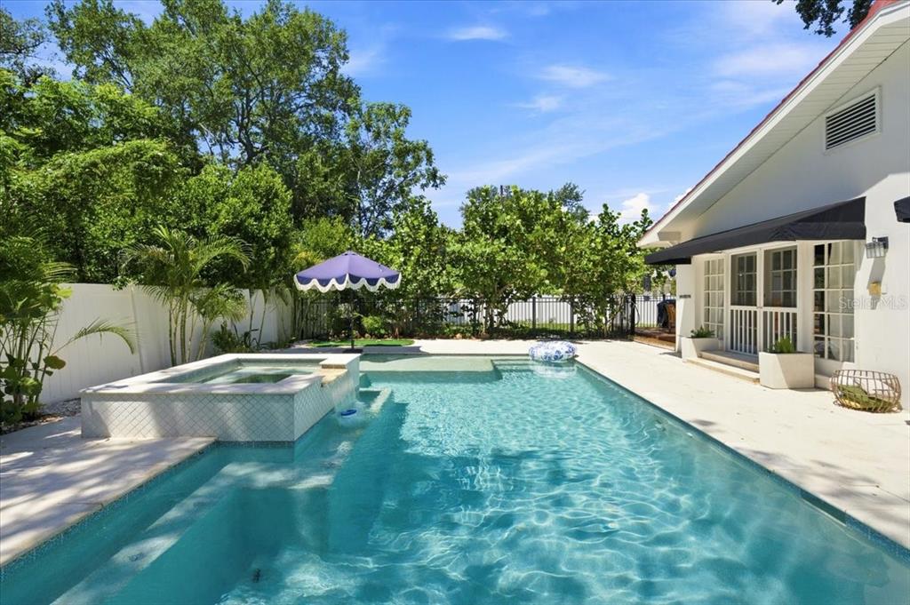 A backyard swimming pool with an attached hot tub and a white house exterior — 222 26TH AVENUE S, ST PETERSBURG, FL