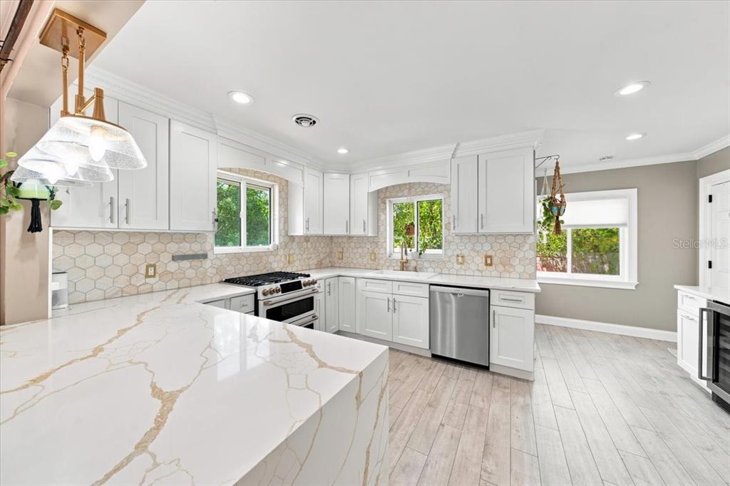 A bright kitchen features white cabinets, gold-veined quartz countertops, and a hexagonal tile backsplash — 222 26TH AVENUE S, ST PETERSBURG, FL