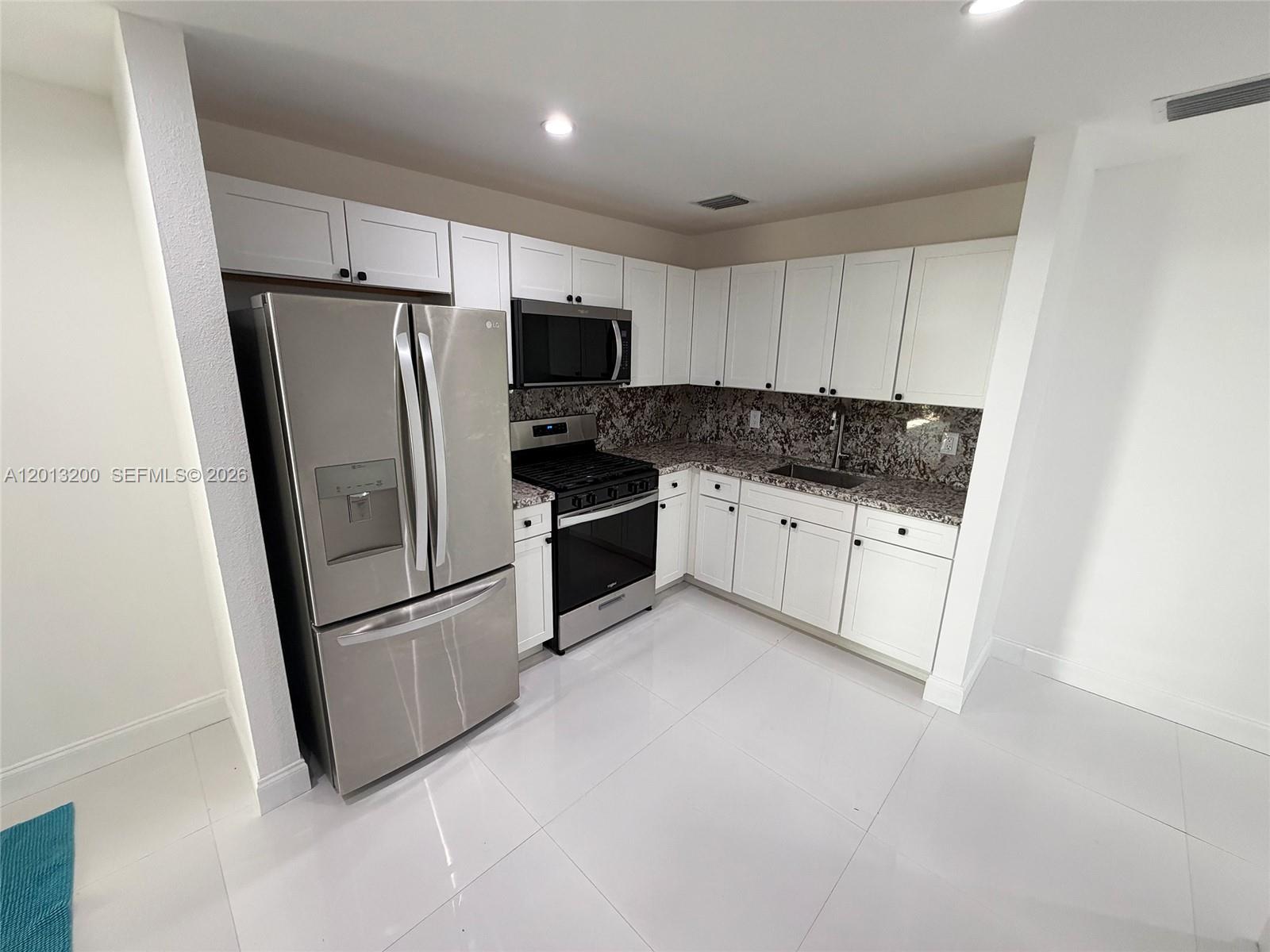 A kitchen features white cabinets, stainless steel appliances, and dark granite countertops — 214 NE 108th, Miami FL 33161, MIAMI, FL