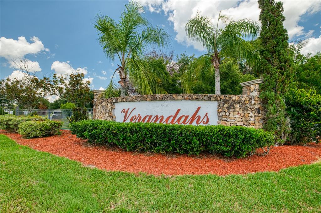 A stone monument sign reading Verandahs stands behind a manicured hedge and palm trees — 3501 BEAU CHENE DRIVE, KISSIMMEE, FL
