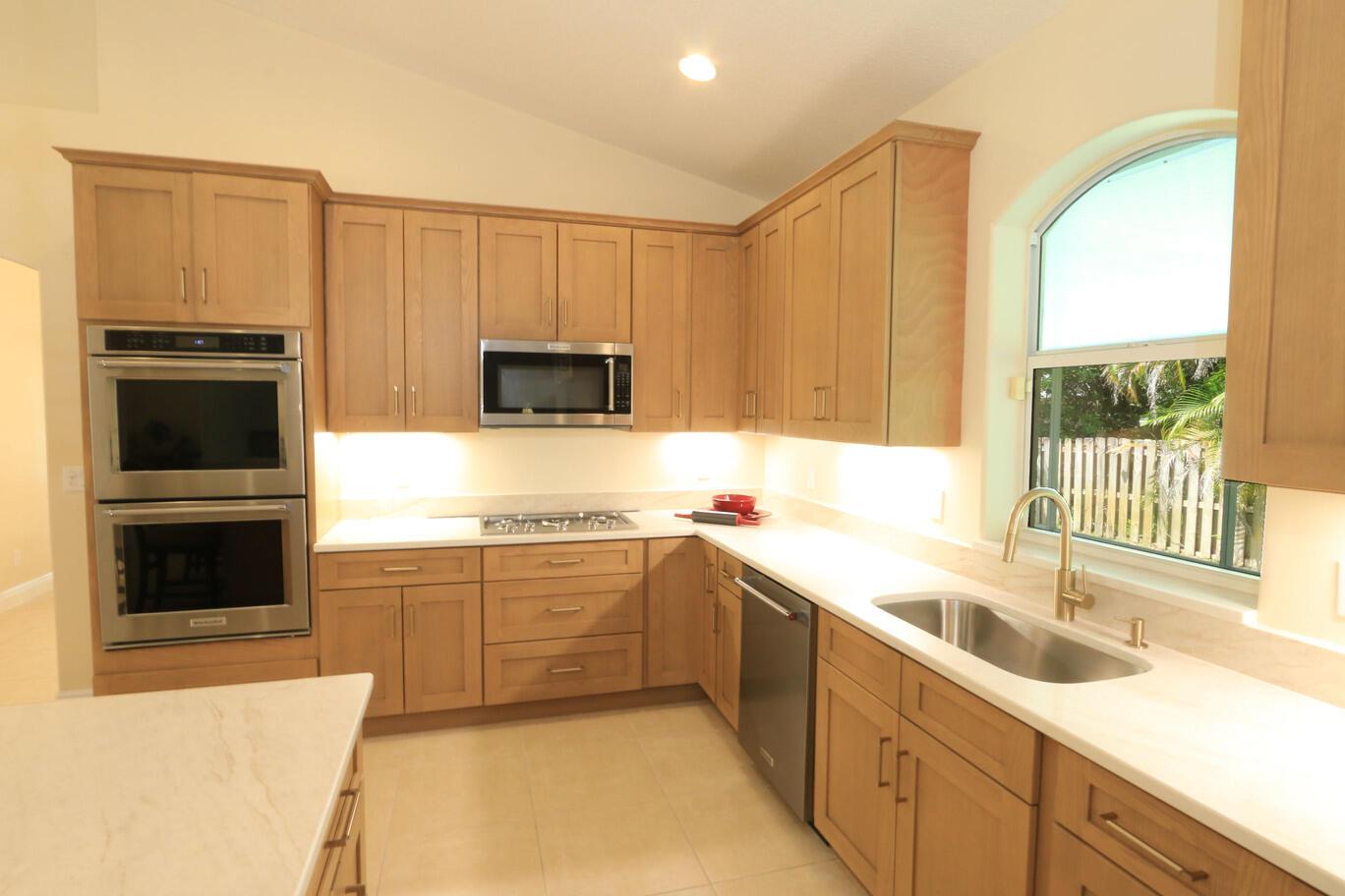 A kitchen with light wood cabinets, a large island, and tile flooring opens to a living area — 2879 SE Peru Street, FL 34984, FL