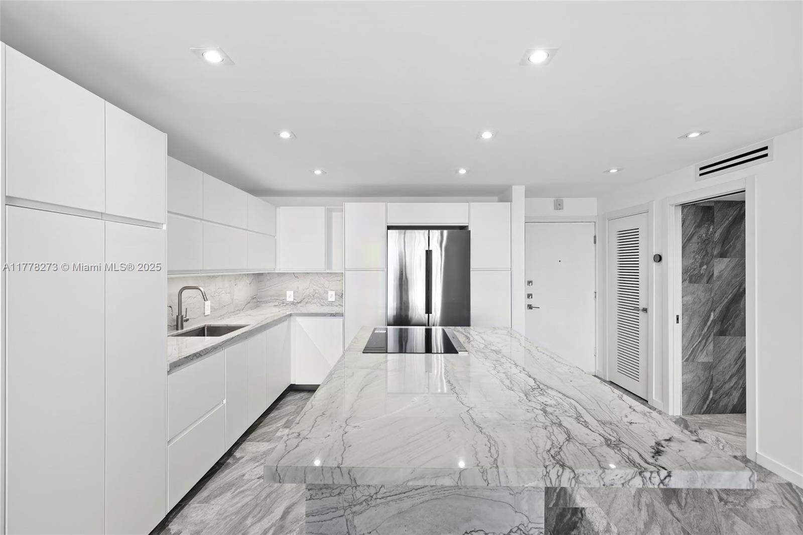 A modern white kitchen features a large marble island, stainless steel appliances, and marble flooring — 1658 Bay Rd # 504, Miami Beach FL 33139, MIAMI BEACH, FL