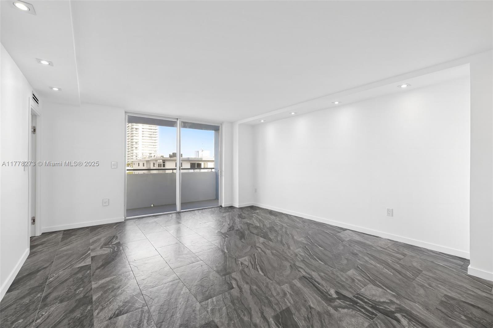 An empty room features white walls, recessed lighting, and dark gray marble-patterned tile flooring — 1658 Bay Rd # 504, Miami Beach FL 33139, MIAMI BEACH, FL