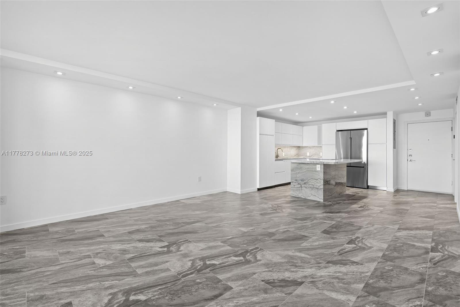An open-concept kitchen and living area features white cabinetry, a marble island, and tiled floors — 1658 Bay Rd # 504, Miami Beach FL 33139, MIAMI BEACH, FL