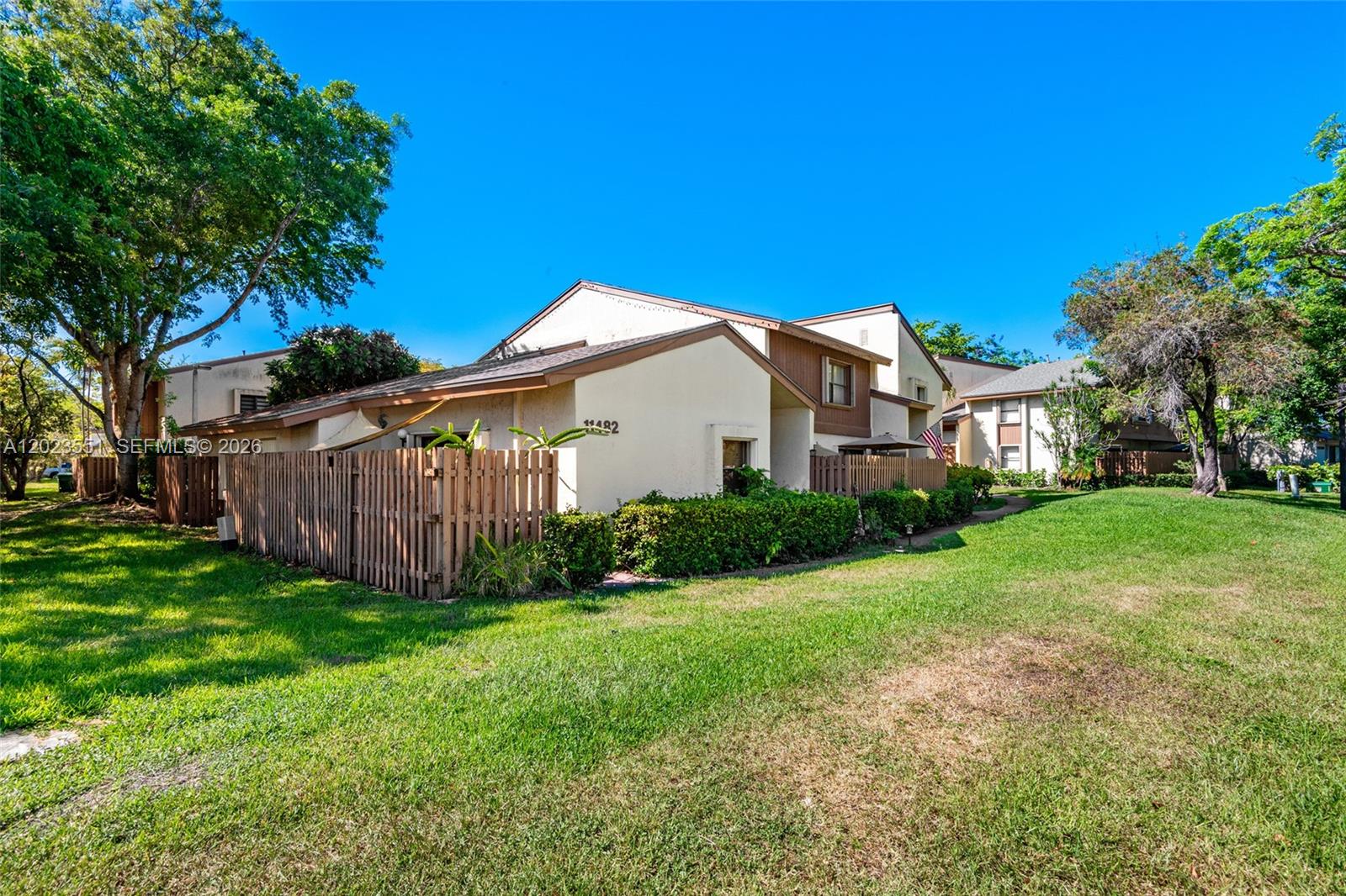 A tan townhouse exterior features a wooden privacy fence and a grassy lawn — 11482 SW 109th Rd # 29A, Miami FL 33176, MIAMI, FL