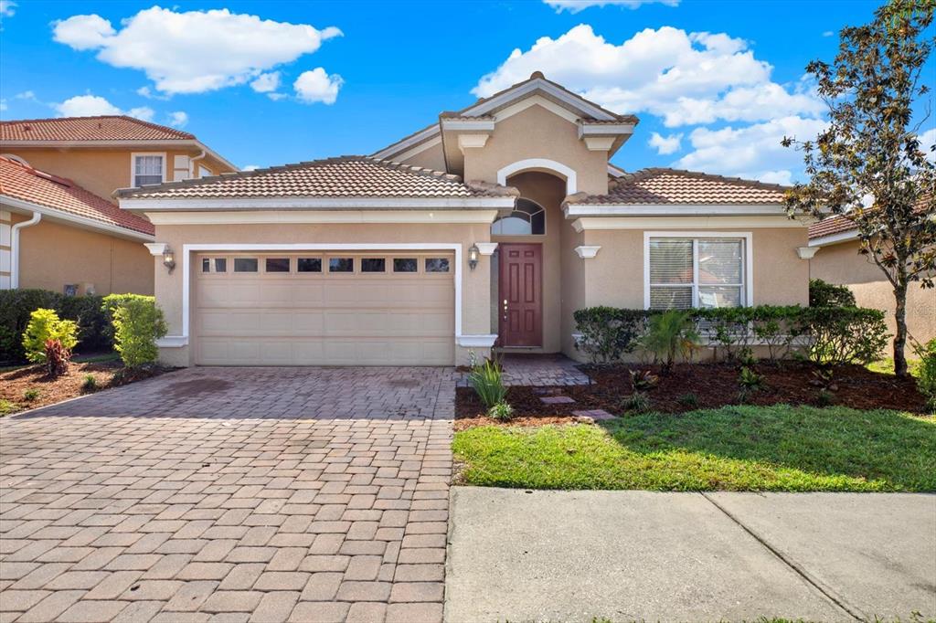 A single-story suburban house with a tan stucco exterior, a two-car garage, and a paved driveway — 18019 JAVA ISLE DRIVE, TAMPA, FL