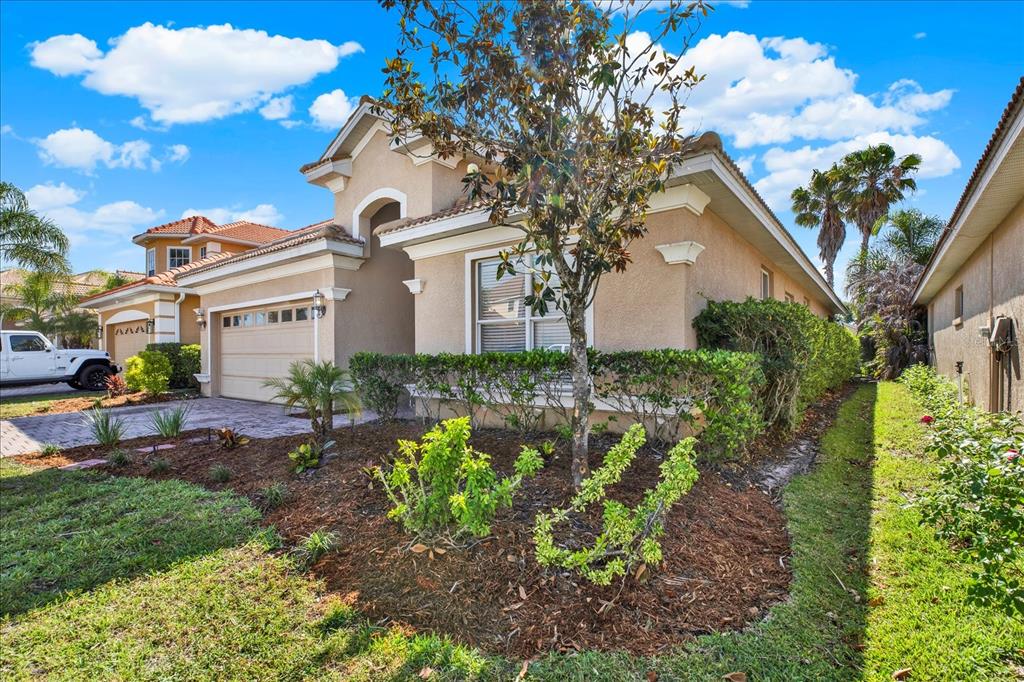 A tan stucco house with a two-car garage and a landscaped front yard — 18019 JAVA ISLE DRIVE, TAMPA, FL
