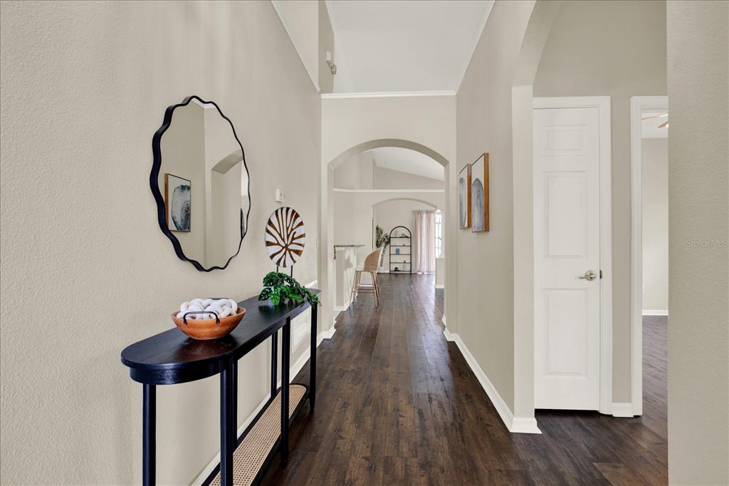 A hallway with dark wood flooring, a console table, a mirror, and arched doorways — 18019 JAVA ISLE DRIVE, TAMPA, FL