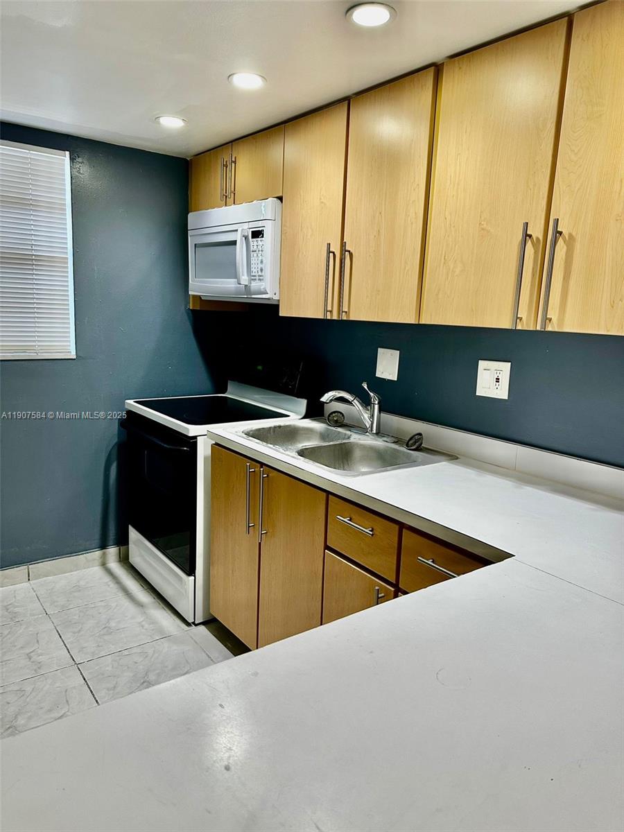 A kitchen features light wood cabinets, a white countertop, and dark gray walls — 8101 SW 73rd Ave # 30, Miami FL 33143, MIAMI, FL