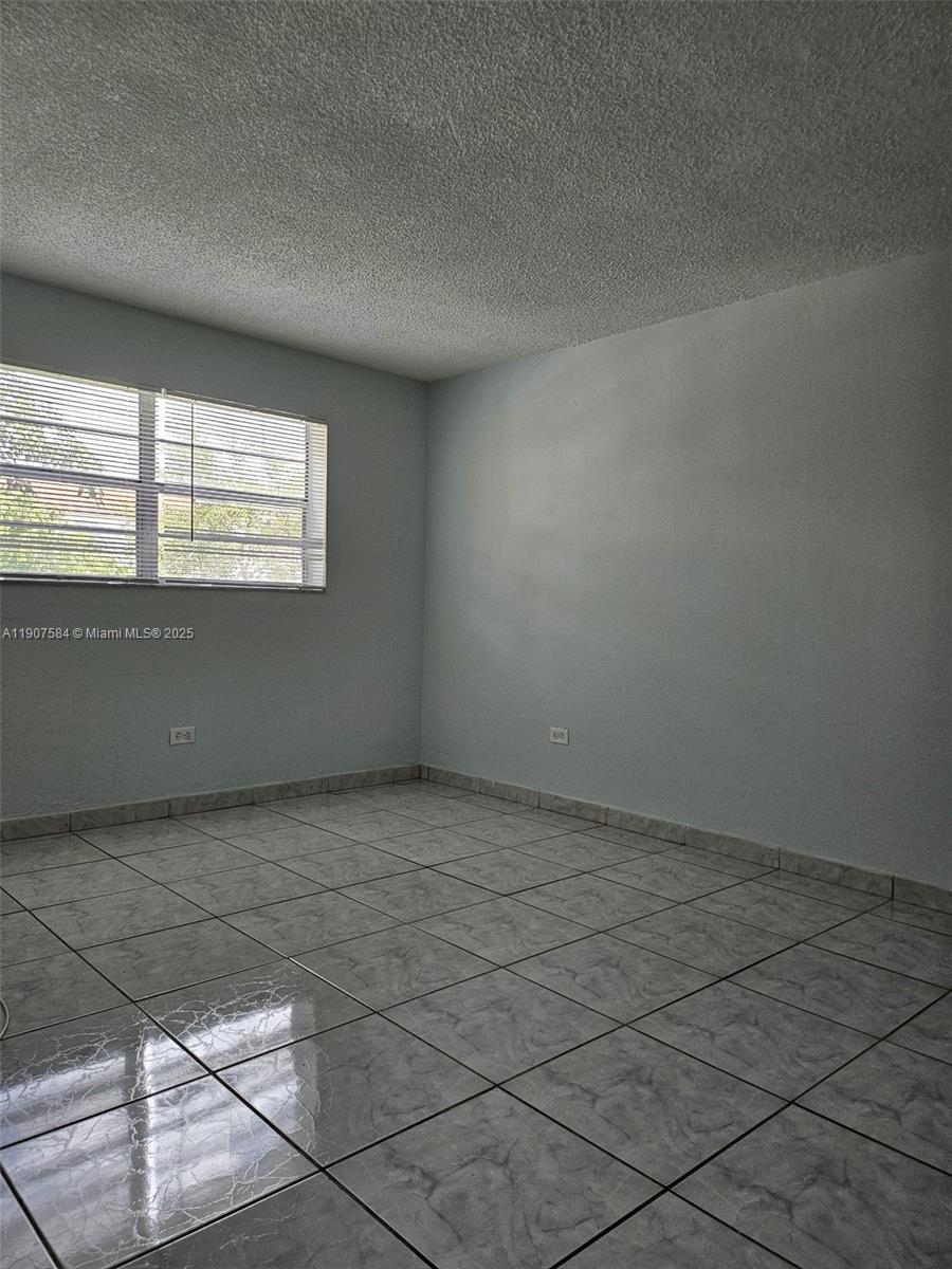 An empty room features light gray walls, a textured ceiling, and light-colored tiled flooring — 8101 SW 73rd Ave # 30, Miami FL 33143, MIAMI, FL