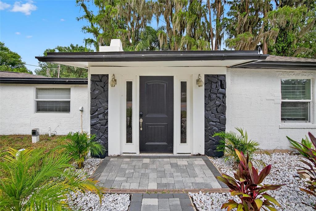 The exterior of a house features a black front door flanked by stone accents — 5028 SCHOOL ROAD, LAND O LAKES, FL