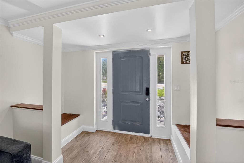 An entryway features a gray front door with sidelights, wood-look tile flooring, and built-in benches — 5028 SCHOOL ROAD, LAND O LAKES, FL