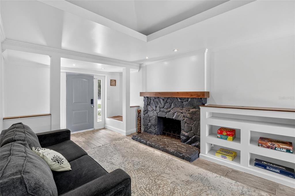 A living room features a stone fireplace, built-in shelving, and a gray front door — 5028 SCHOOL ROAD, LAND O LAKES, FL