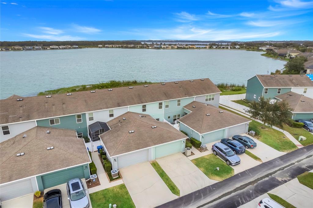 An aerial view shows a row of townhouses with garages and driveways facing a lake — 513 JUNIPER SPRINGS DRIVE, GROVELAND, FL