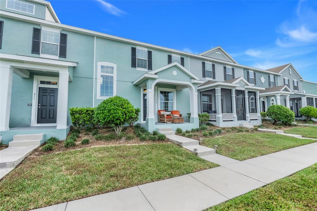 A row of light blue townhouses with covered porches and small front lawns — 513 JUNIPER SPRINGS DRIVE, GROVELAND, FL