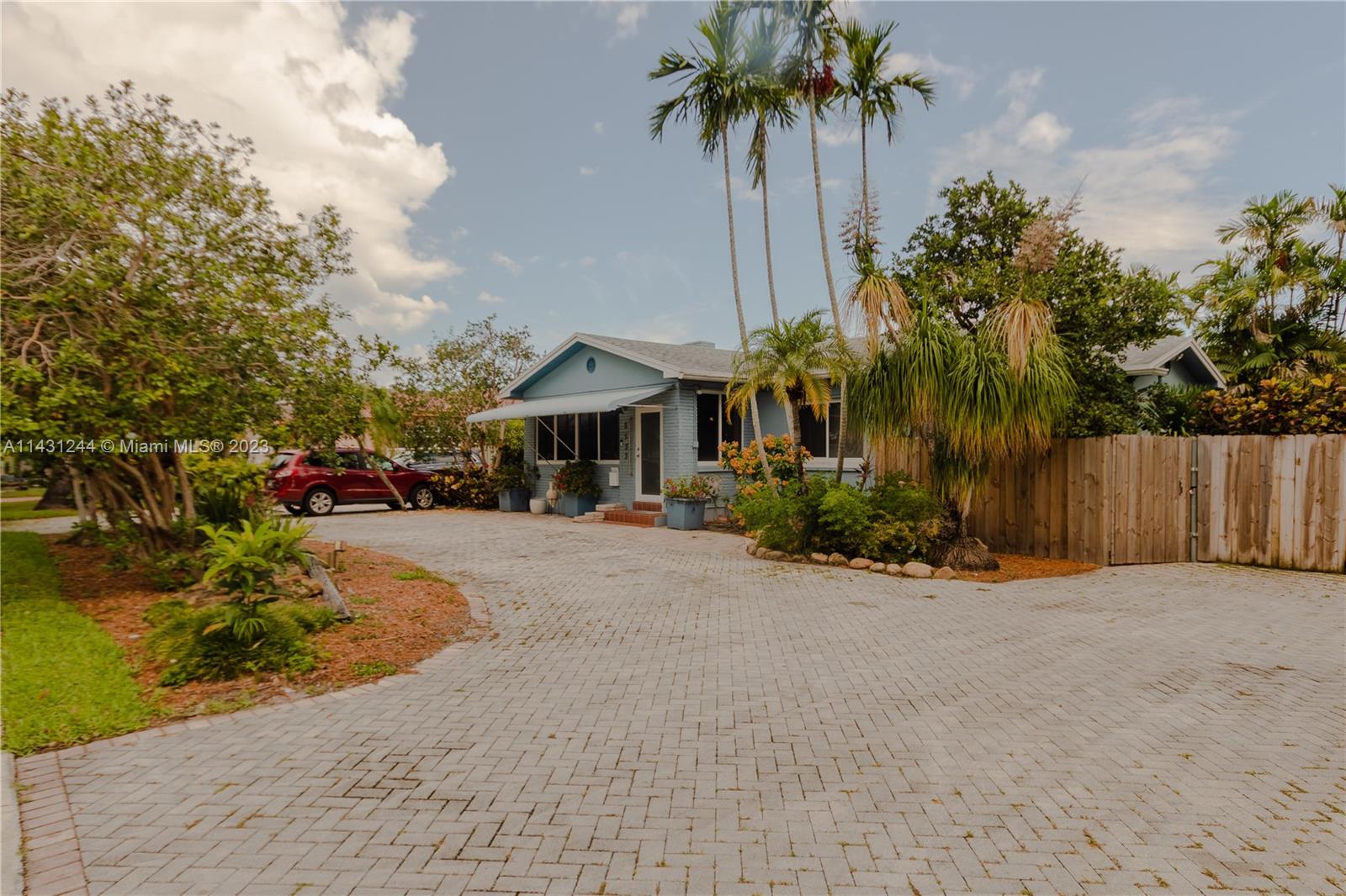 A light blue house with a brick facade sits behind a large paved driveway — 2533 Fillmore St, Hollywood FL 33020, HOLLYWOOD, FL