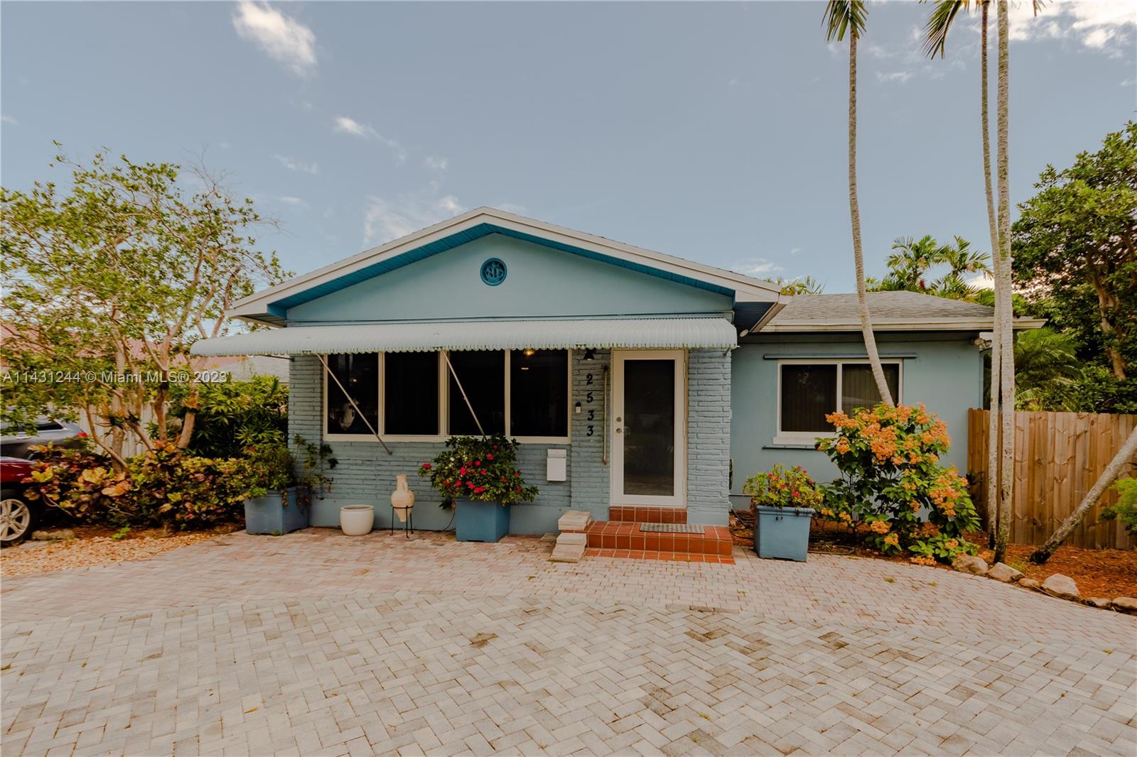 A light blue single-story house features a brick facade, a white awning, and a paved driveway — 2533 Fillmore St, Hollywood FL 33020, HOLLYWOOD, FL