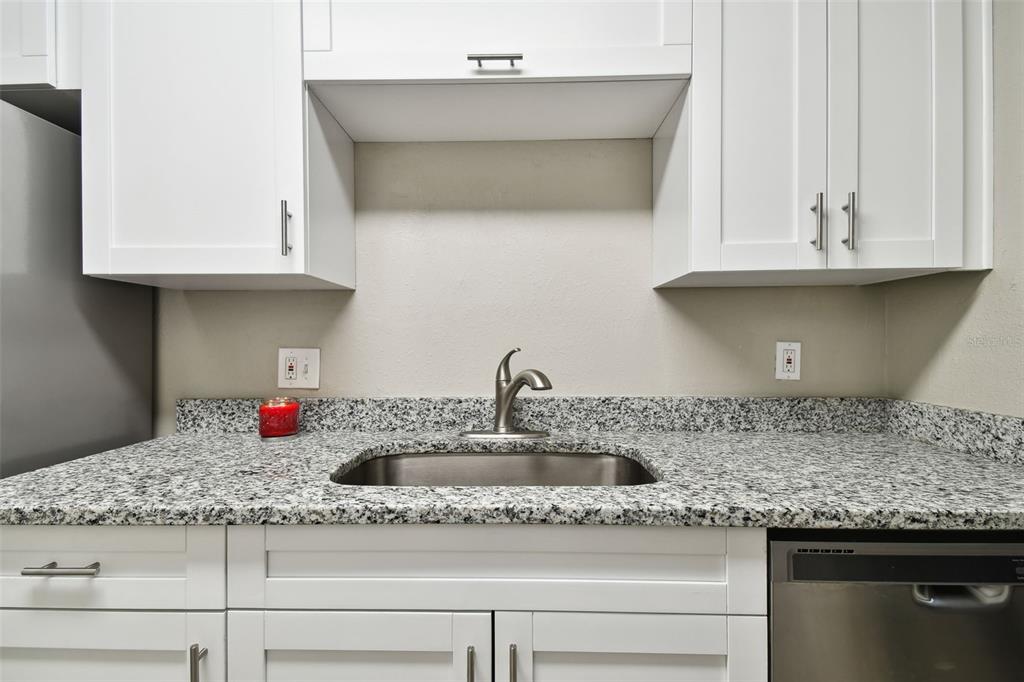 A kitchen sink with a granite countertop and white cabinets — 7504 PRESLEY PLACE UNIT 115 C, TAMPA, FL