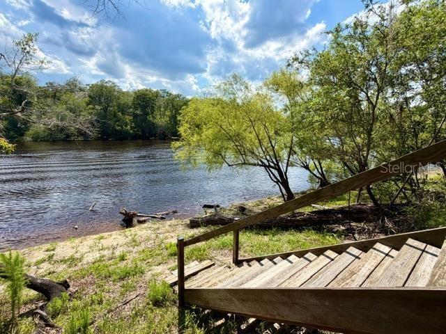 A wooden staircase leads down a grassy bank to a river surrounded by trees — 1109 NW 78TH AVENUE, BELL, FL