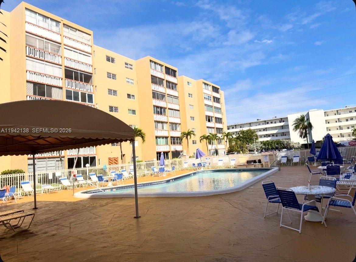 An outdoor swimming pool area with lounge chairs and umbrellas in front of apartment buildings — 420 NE 12th Ave # 502, Hallandale Beach FL 33009, HALLANDALE BEACH, FL