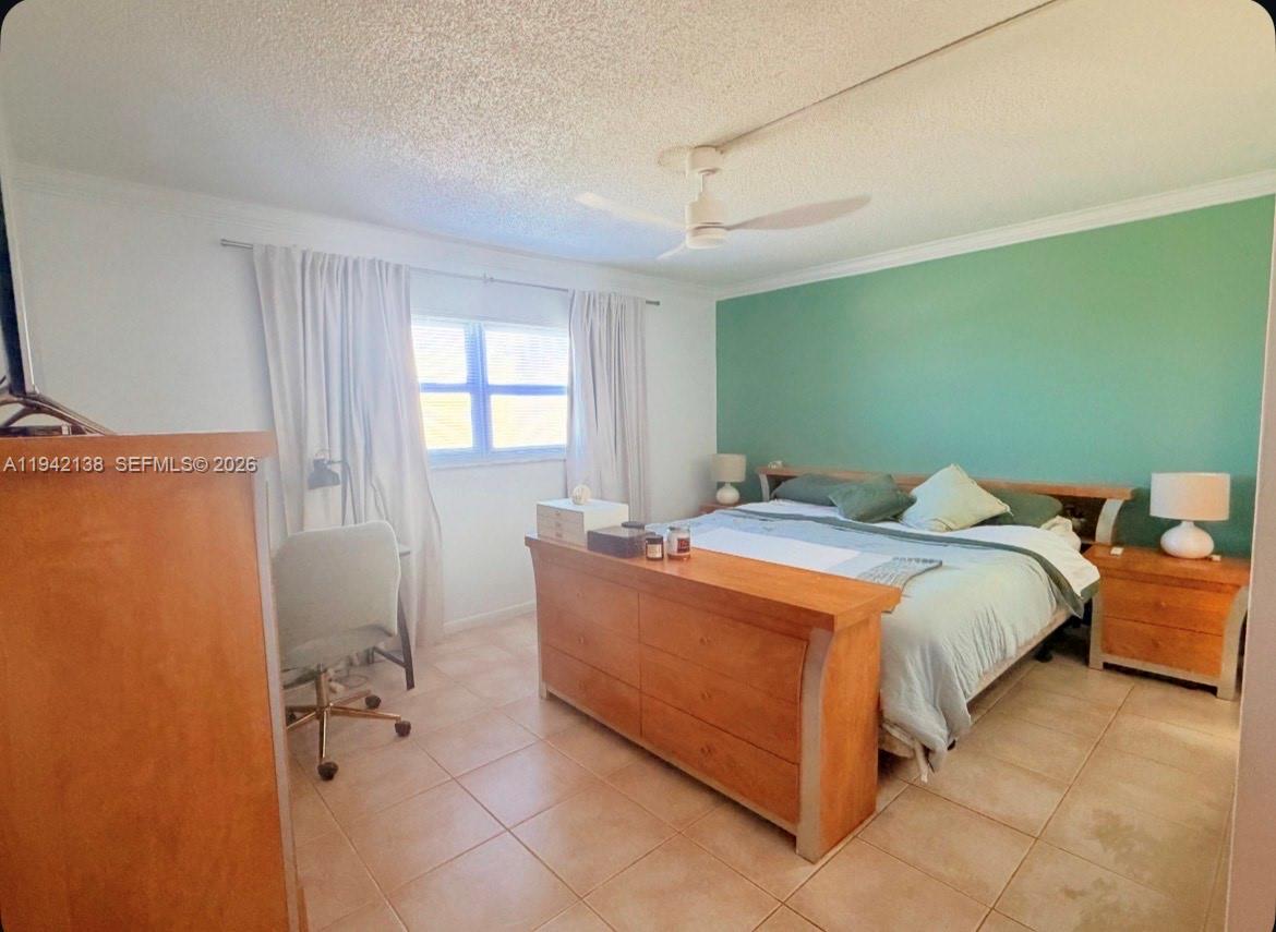 A bedroom features a bed with a wooden footboard, a green accent wall, and tile flooring — 420 NE 12th Ave # 502, Hallandale Beach FL 33009, HALLANDALE BEACH, FL