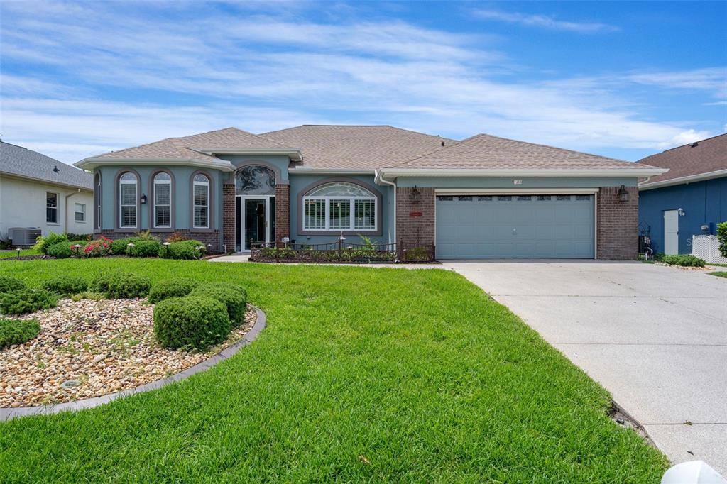 A single-story house with a brick facade, blue siding, and a two-car garage — 7450 ALOE DRIVE, SPRING HILL, FL