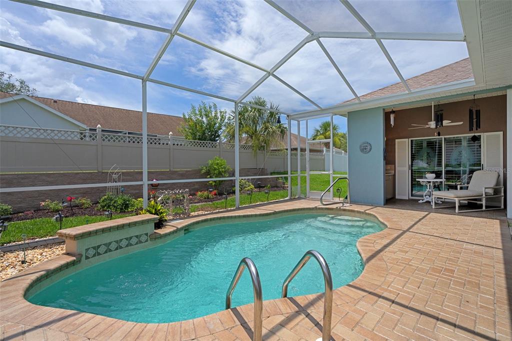 A screened-in patio features a kidney-shaped swimming pool with a brick paver deck — 7450 ALOE DRIVE, SPRING HILL, FL