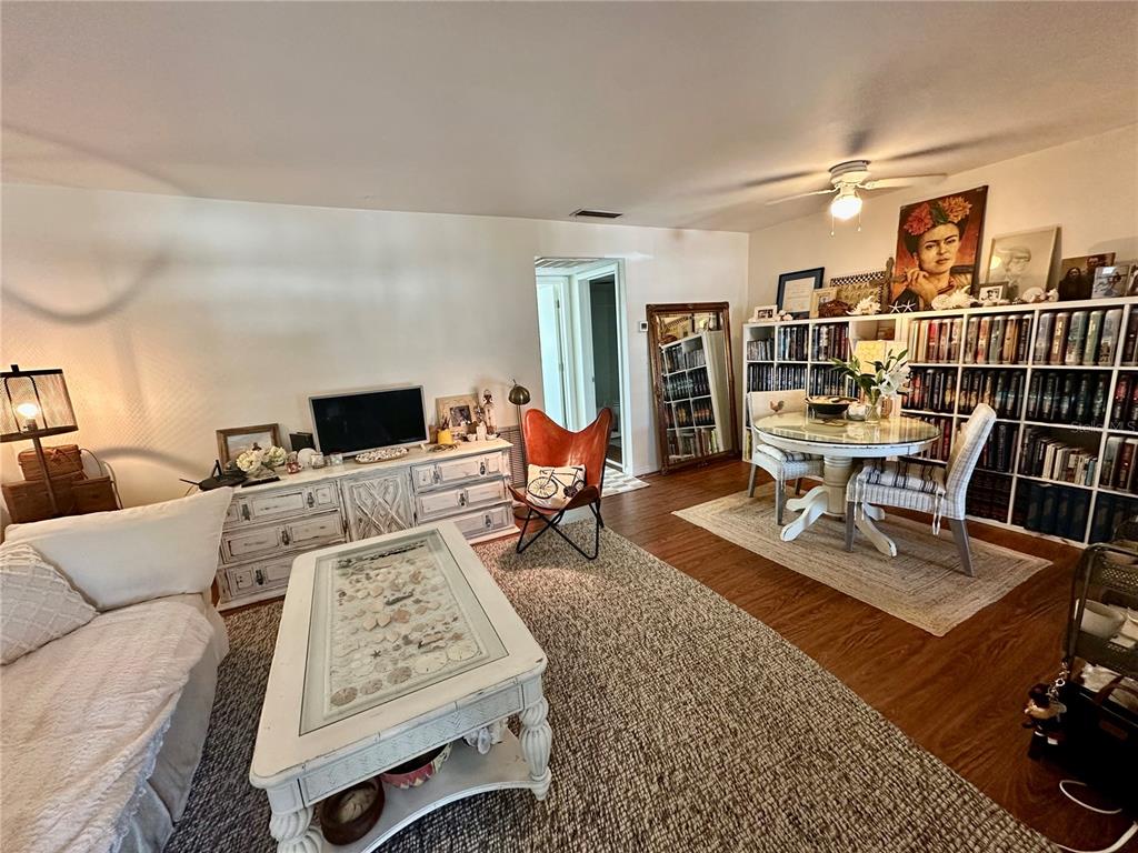 A living room features a white coffee table, a dining area with bookshelves, and wood flooring — 1221 DREW STREET UNIT D9, CLEARWATER, FL