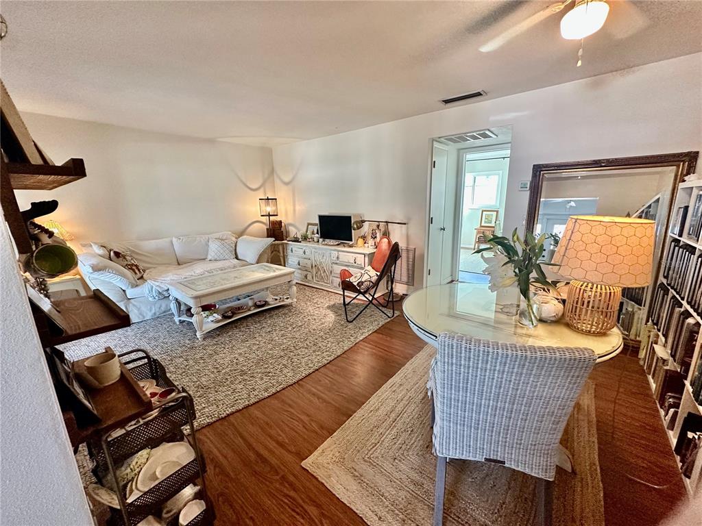 A living and dining area features wood-look flooring, a white sofa, and a round table — 1221 DREW STREET UNIT D9, CLEARWATER, FL