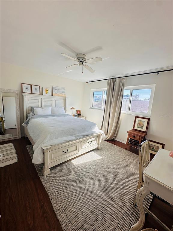 A bedroom features a white bed, a large area rug, a ceiling fan, and windows — 1221 DREW STREET UNIT D9, CLEARWATER, FL