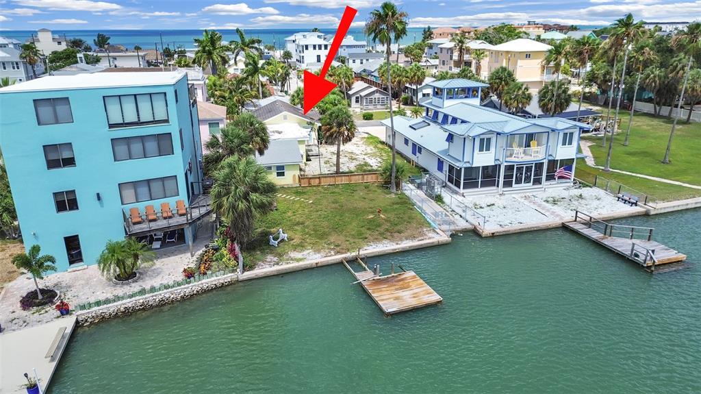 An aerial view shows a waterfront property with a small house between two larger buildings — 201 90TH AVENUE, TREASURE ISLAND, FL