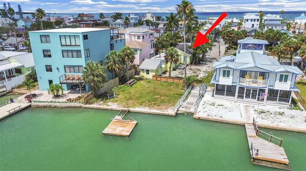 An aerial view of a waterfront property featuring a small yellow house and two docks — 201 90TH AVENUE, TREASURE ISLAND, FL