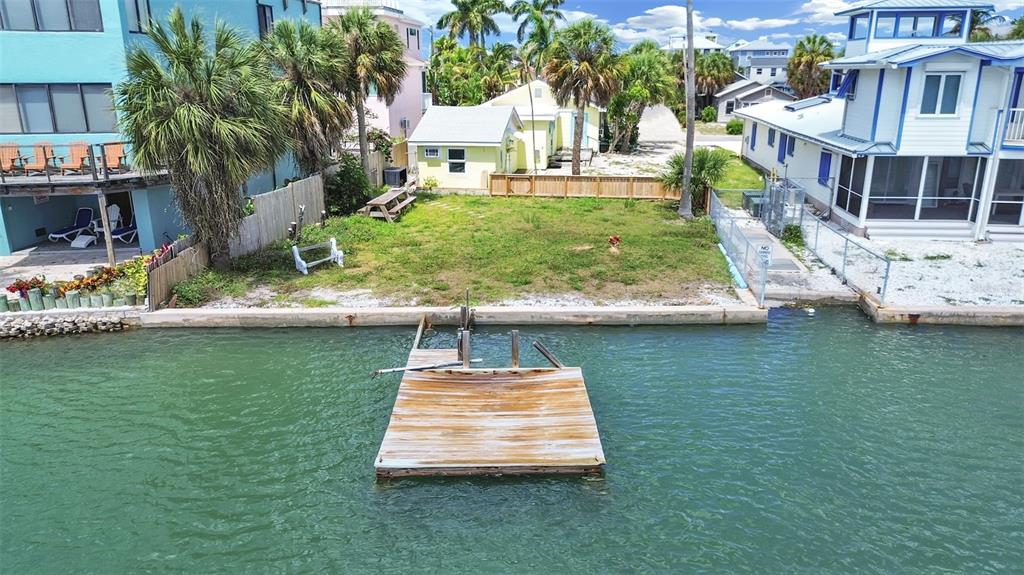 An aerial view of a vacant waterfront lot featuring a wooden dock and surrounding houses — 201 90TH AVENUE, TREASURE ISLAND, FL