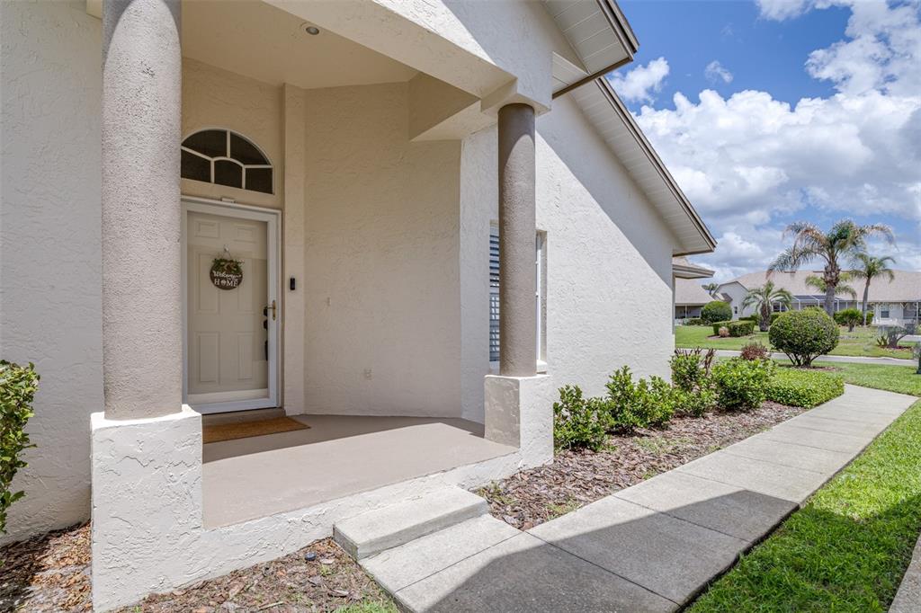 A covered entryway with two columns leads to a front door with a transom window — 6866 BENDELOW DRIVE, LAKELAND, FL