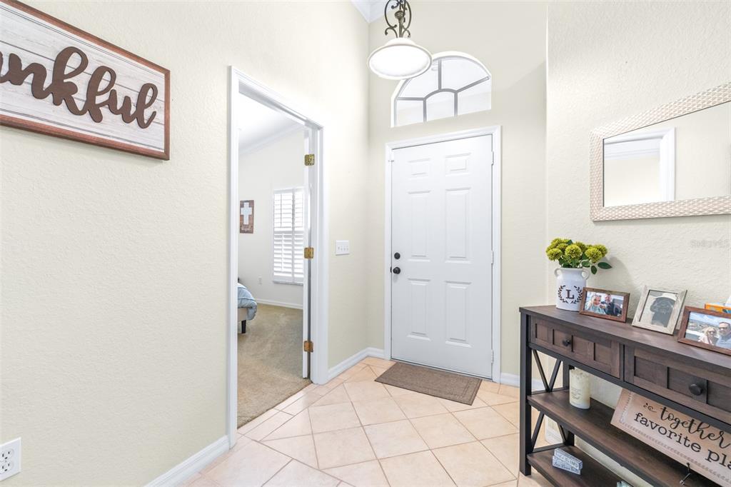 An entryway features a white front door, tile flooring, and a wooden console table — 6866 BENDELOW DRIVE, LAKELAND, FL