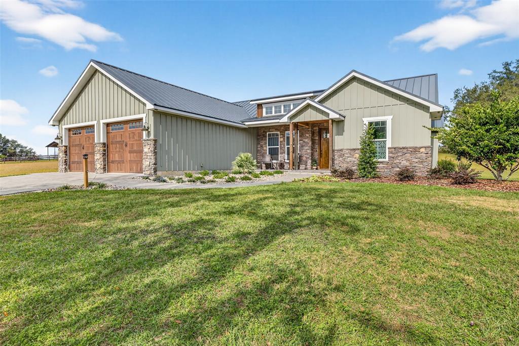 A single-story house with a metal roof, board-and-batten siding, and stone accents — 32103 RUSTY CREEK TRAIL, DADE CITY, FL