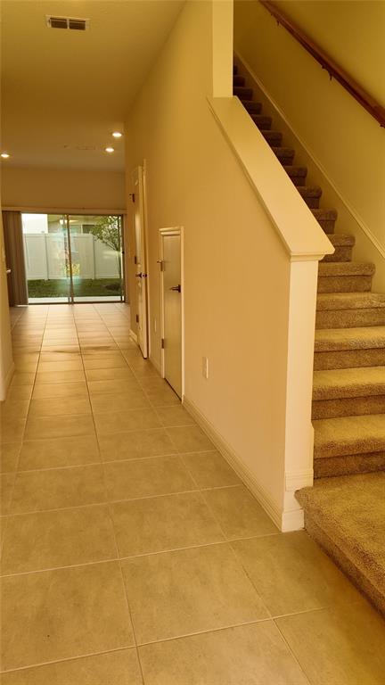 A tiled hallway leads to a sliding glass door with stairs on the right — 2207 PORTRAIT STREET, KISSIMMEE, FL