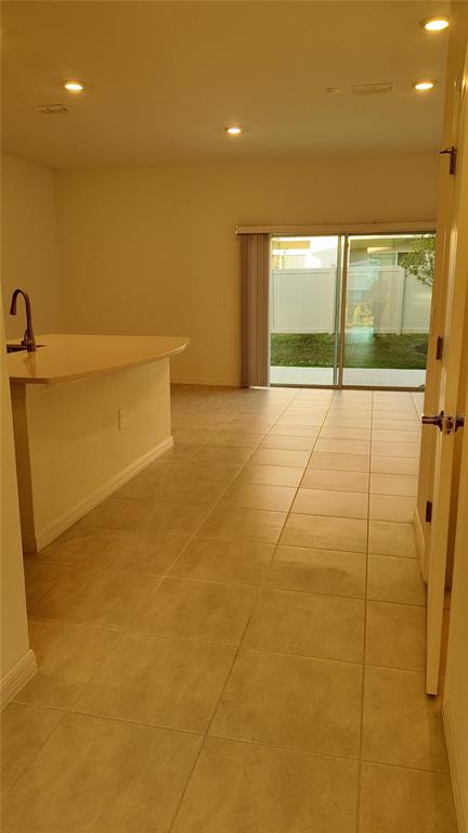 An open-concept kitchen with a breakfast bar overlooks a living area with sliding glass doors — 2207 PORTRAIT STREET, KISSIMMEE, FL
