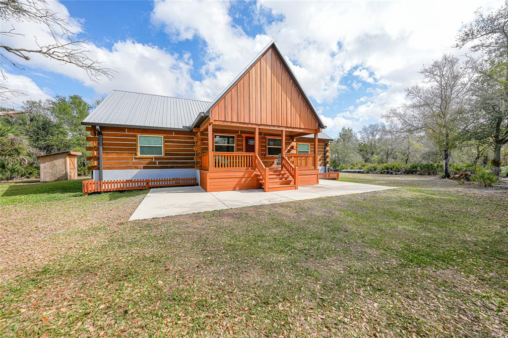 A log cabin with a metal roof and a wooden porch sits on a grassy lot — 9796 SW SOUTHERN DREAMS ROAD, ARCADIA, FL