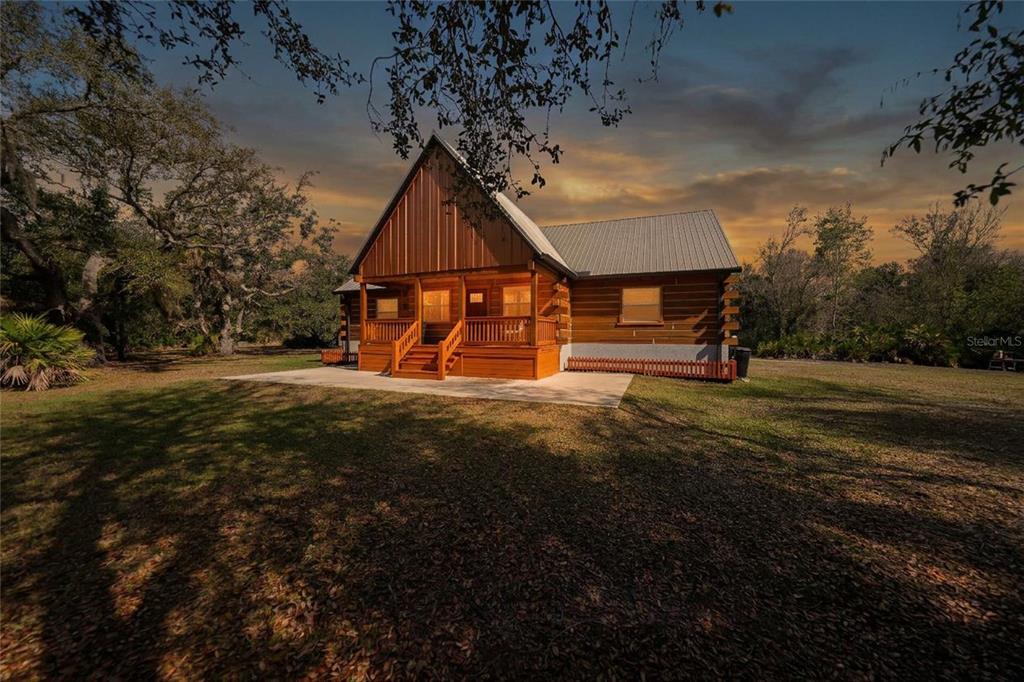 A wooden cabin with a metal roof and a front porch sits on a grassy lot — 9796 SW SOUTHERN DREAMS ROAD, ARCADIA, FL