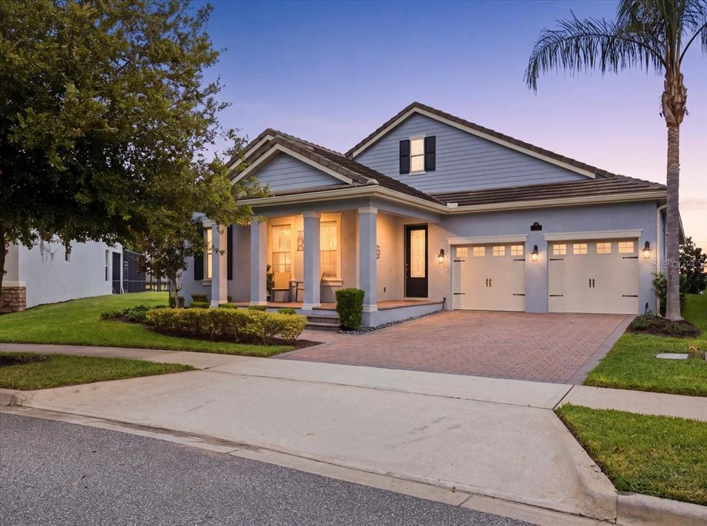 A light blue single-story house with a brick driveway and a covered front porch — 10043 LITTLE ALCOVE LOOP, WINTER GARDEN, FL