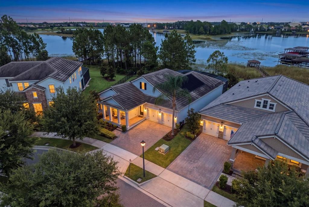 An aerial view shows three suburban houses with tiled roofs situated along a lake at dusk — 10043 LITTLE ALCOVE LOOP, WINTER GARDEN, FL