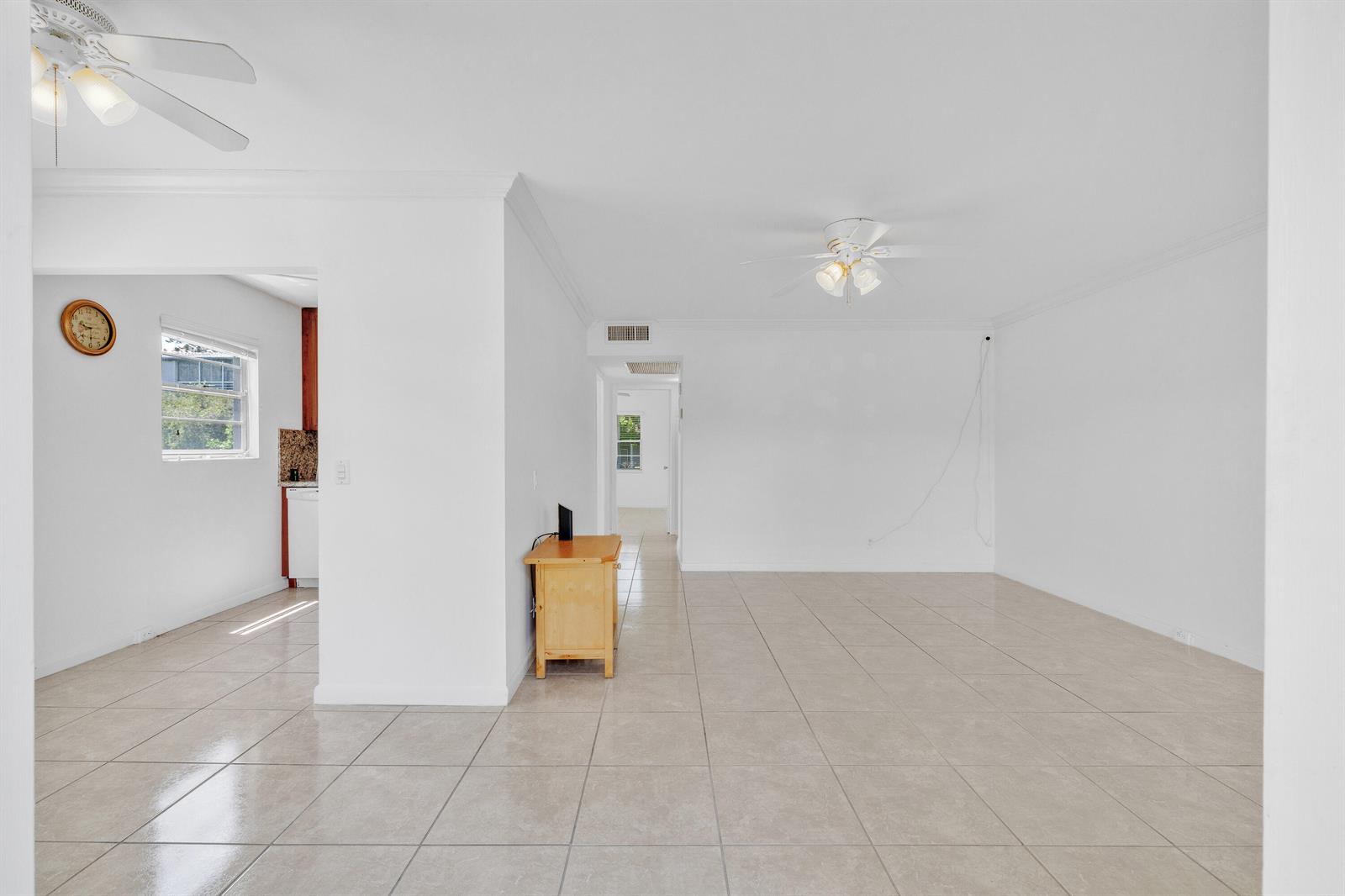 A bright, tiled living area features white walls, two ceiling fans, and an adjacent kitchen — 169 Suffolk E, Boca Raton FL 33434, BOCA RATON, FL