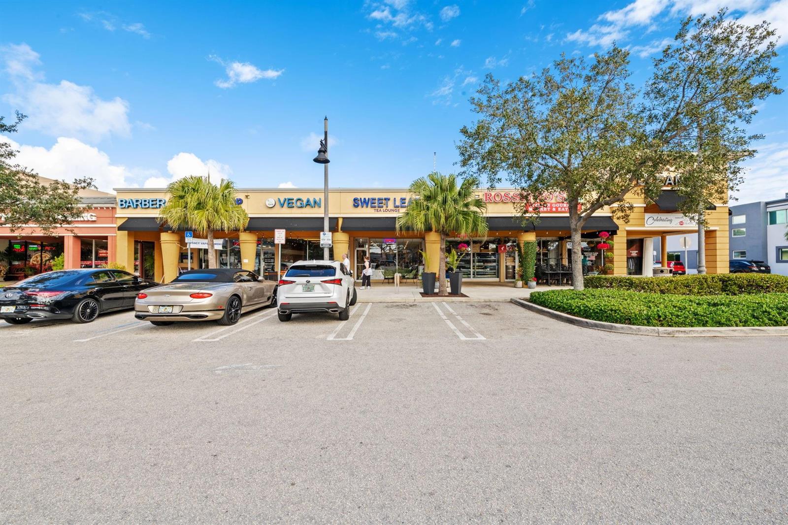 A parking lot sits in front of a strip mall with several storefronts and palm trees — 2667 E Atlantic Boulevard, Pompano Beach FL 33062, POMPANO BEACH, FL