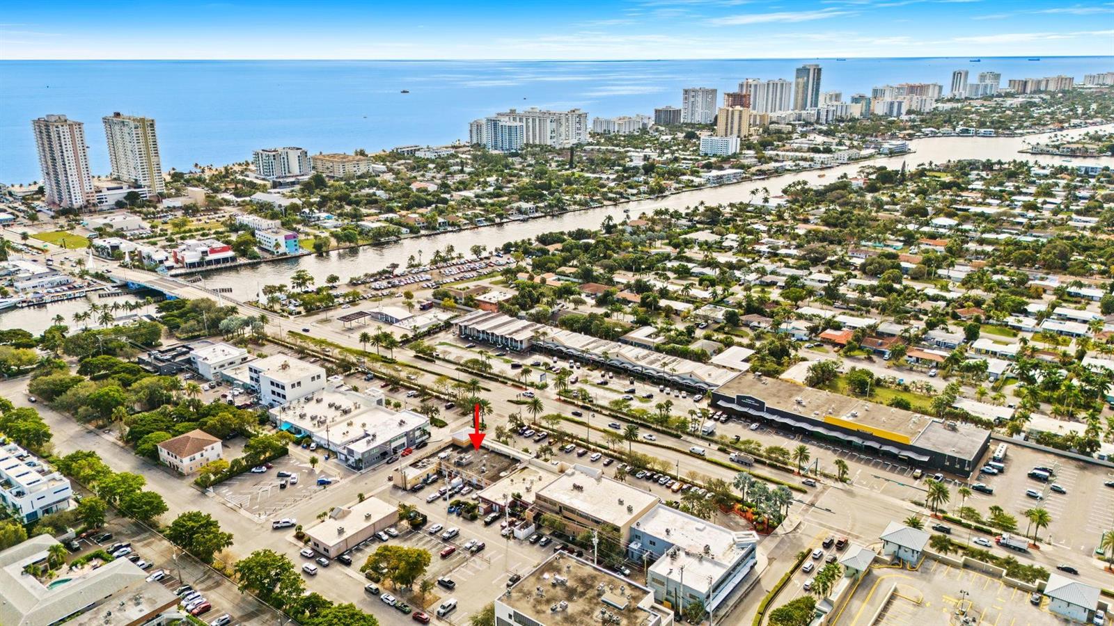 An aerial view shows a coastal city with a red arrow pointing to a building — 2667 E Atlantic Boulevard, Pompano Beach FL 33062, POMPANO BEACH, FL