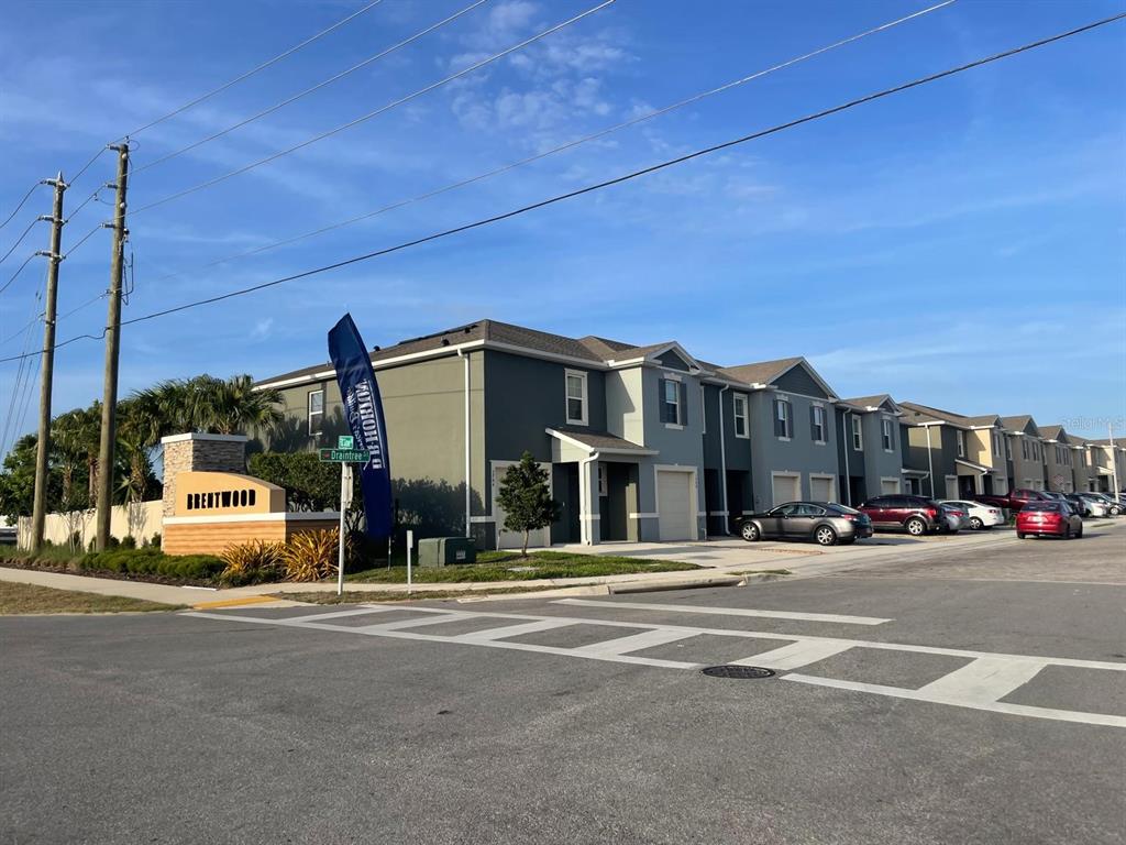 A street-level view of a modern multi-unit residential building with a Brentwood community sign — 1428 PLANK PLACE, DAVENPORT, FL